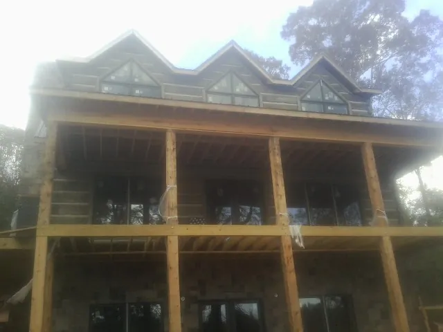 Dormers and porch framing on a large log home under construction — Roof Coating work by our crew in Farwell