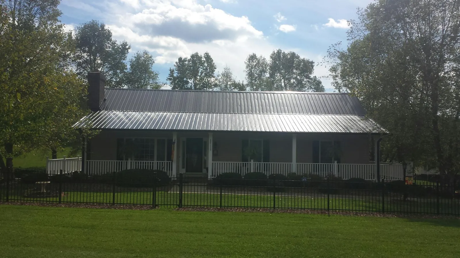 Gray metal roof on a brick ranch with a full width front porch — Gutter Guard Installation work by our crew in Farwell