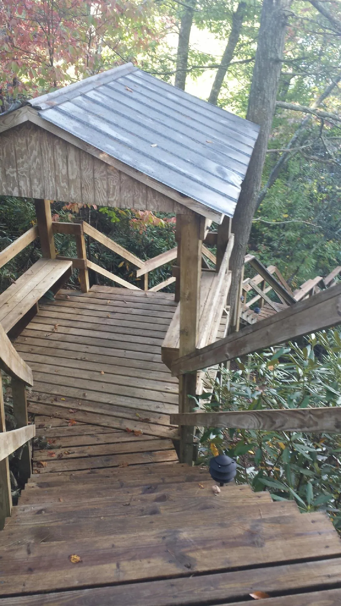 Metal roofed shelter over wooden steps on a wooded walkway — Skylight Repair & Installation work by our crew in Farwell